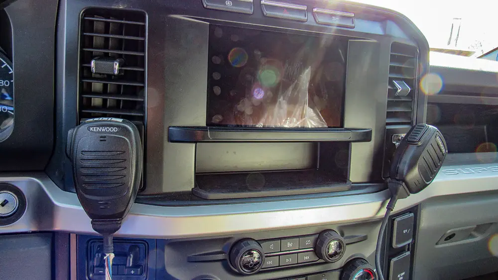 Exterior view of small fire truck showing cab, body compartments, and wheel/tire area.