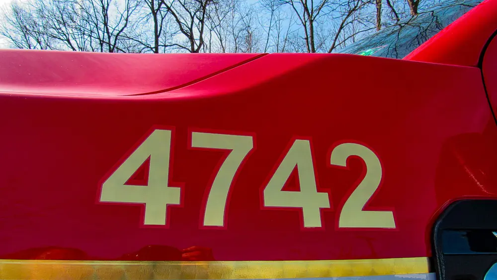 Exterior view of small fire truck showing cab, body compartments, and wheel/tire area.