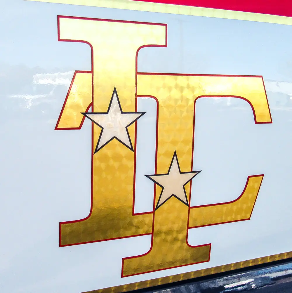 Exterior view of small fire truck showing cab, body compartments, and wheel/tire area.