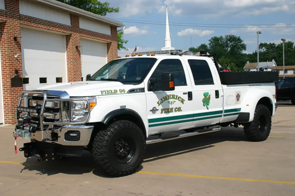 Exterior view of small fire truck showing cab, body compartments, and wheel/tire area.