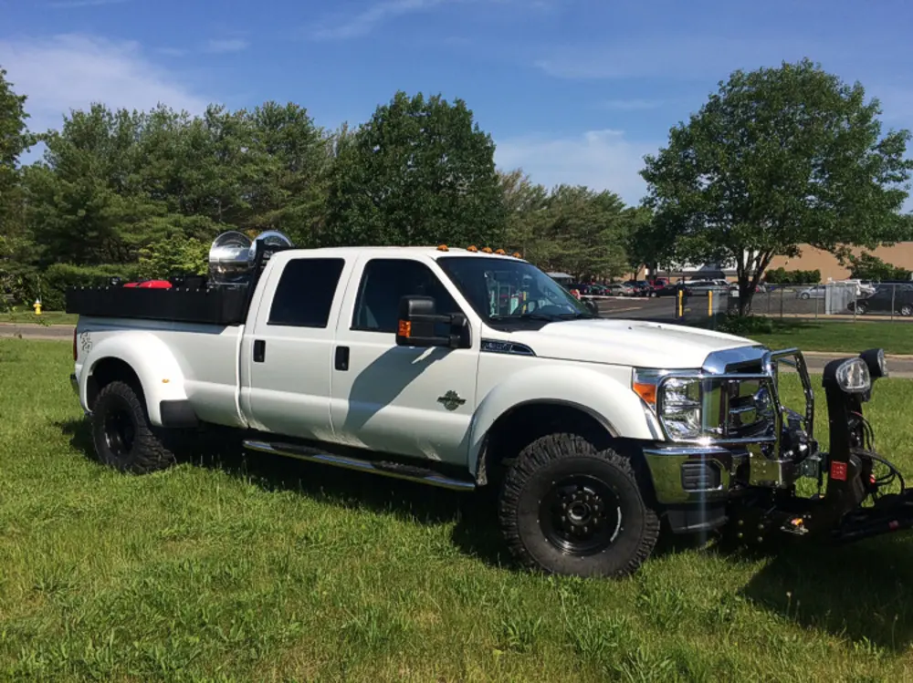 Exterior view of small fire truck showing cab, body compartments, and wheel/tire area.