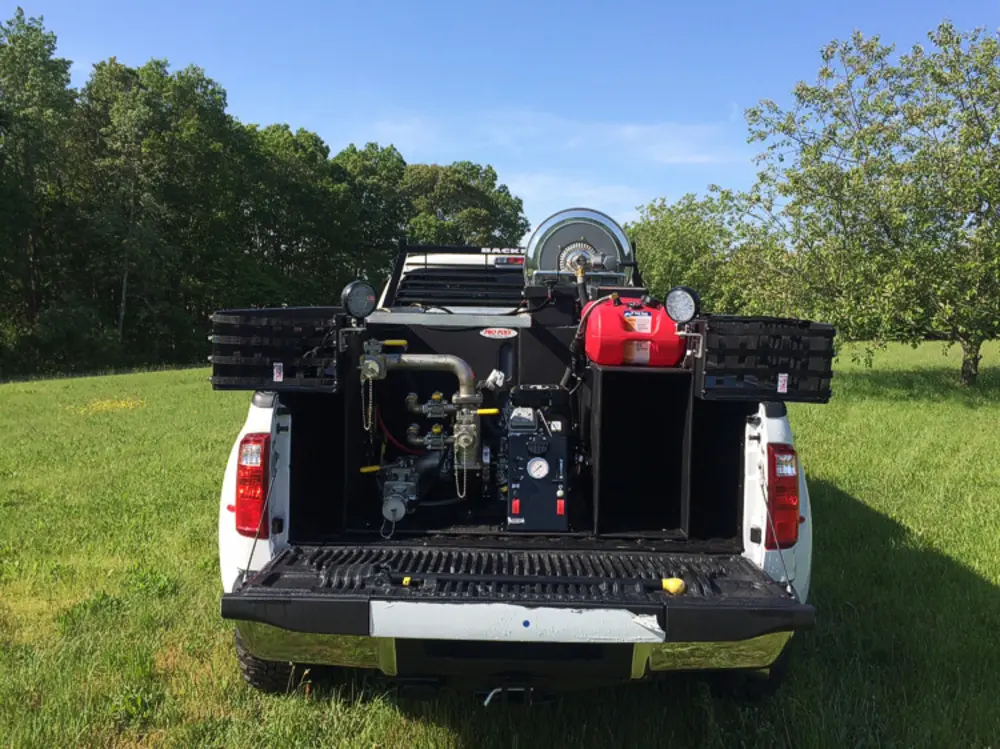 Exterior view of small fire truck showing cab, body compartments, and wheel/tire area.