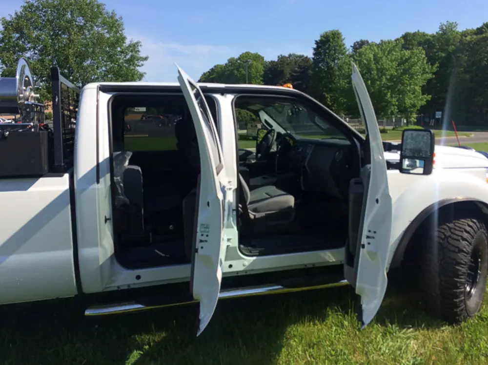Exterior view of small fire truck showing cab, body compartments, and wheel/tire area.