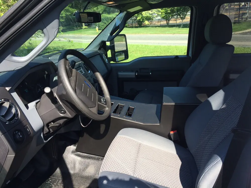 Exterior view of small fire truck showing cab, body compartments, and wheel/tire area.