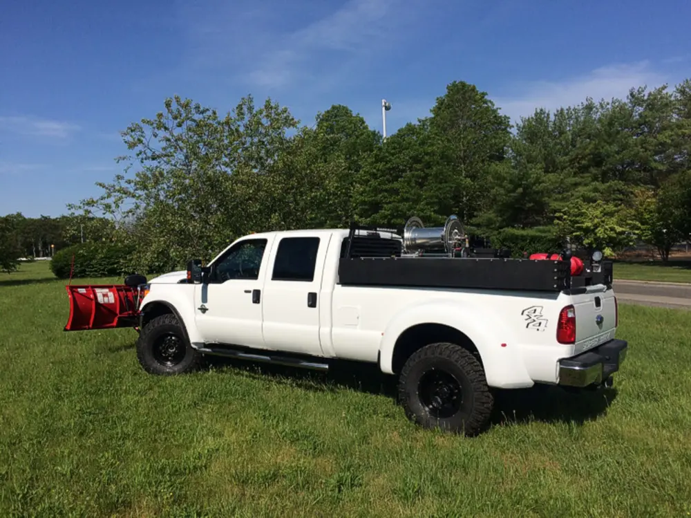 Exterior view of small fire truck showing cab, body compartments, and wheel/tire area.