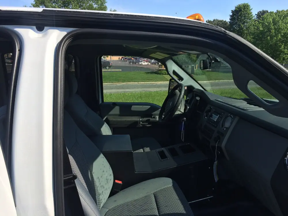 Exterior view of small fire truck showing cab, body compartments, and wheel/tire area.