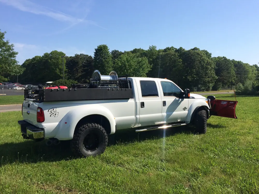 Exterior view of small fire truck showing cab, body compartments, and wheel/tire area.