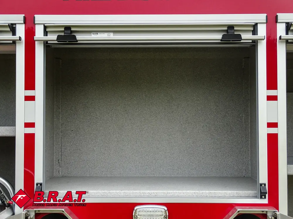 Exterior view of small fire truck showing cab, body compartments, and wheel/tire area.