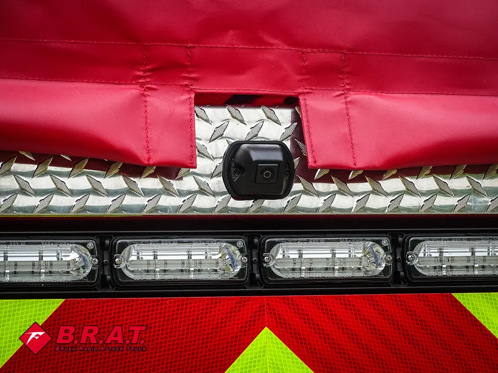 Exterior view of small fire truck showing cab, body compartments, and wheel/tire area.