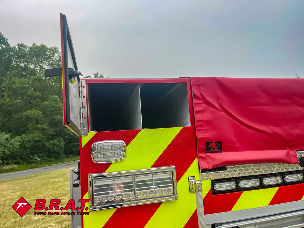 Exterior view of small fire truck showing cab, body compartments, and wheel/tire area.