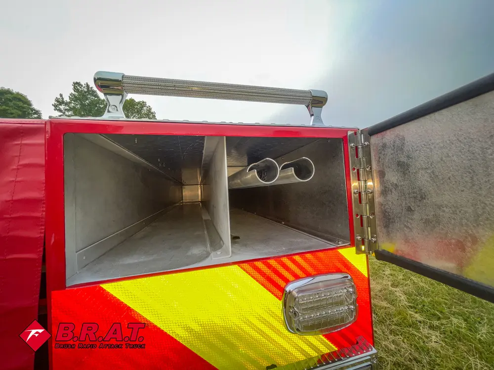 Exterior view of small fire truck showing cab, body compartments, and wheel/tire area.