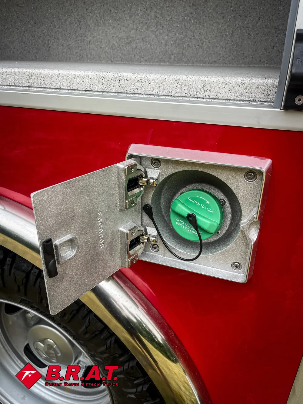 Exterior view of small fire truck showing cab, body compartments, and wheel/tire area.