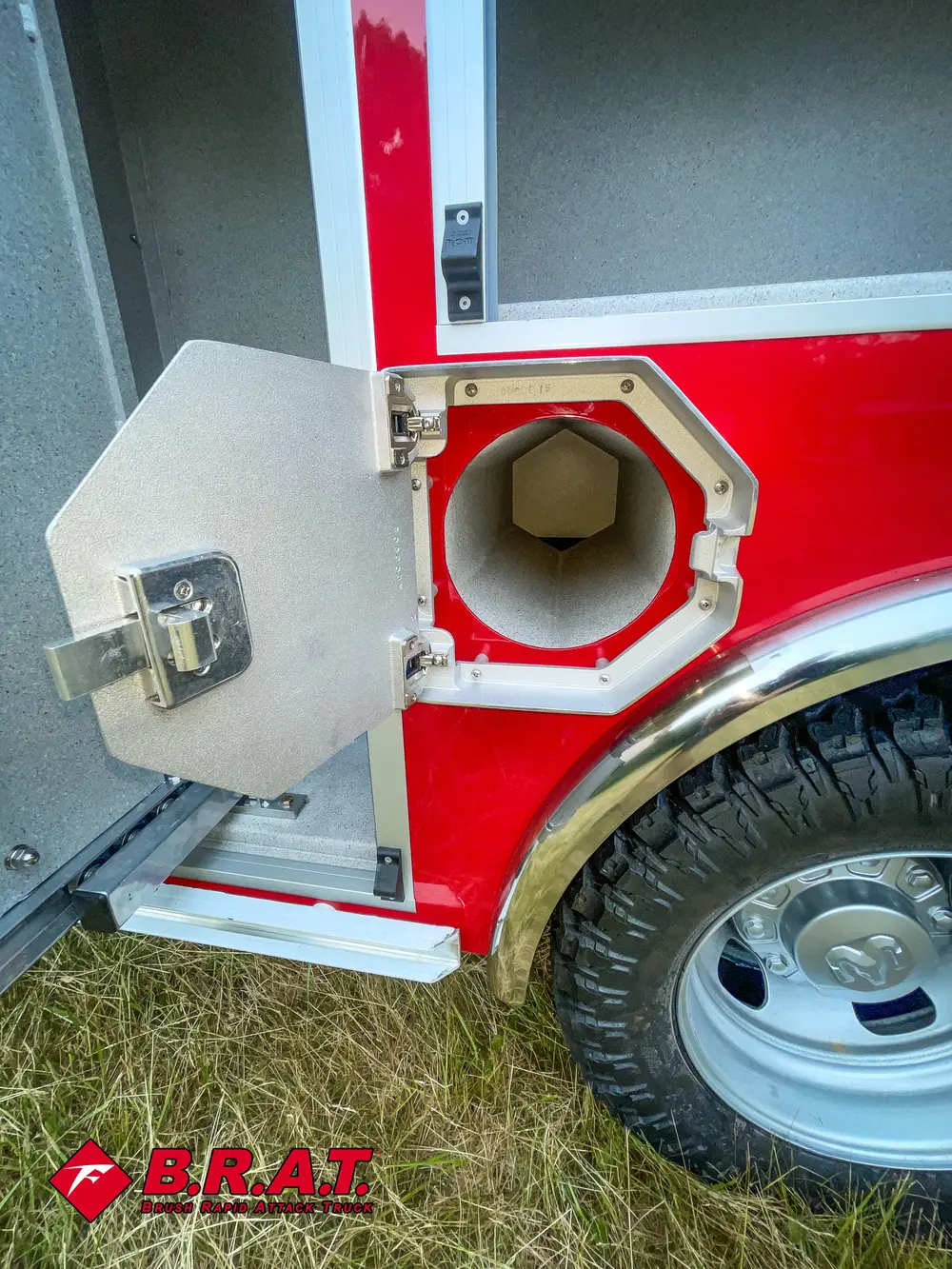 Exterior view of small fire truck showing cab, body compartments, and wheel/tire area.