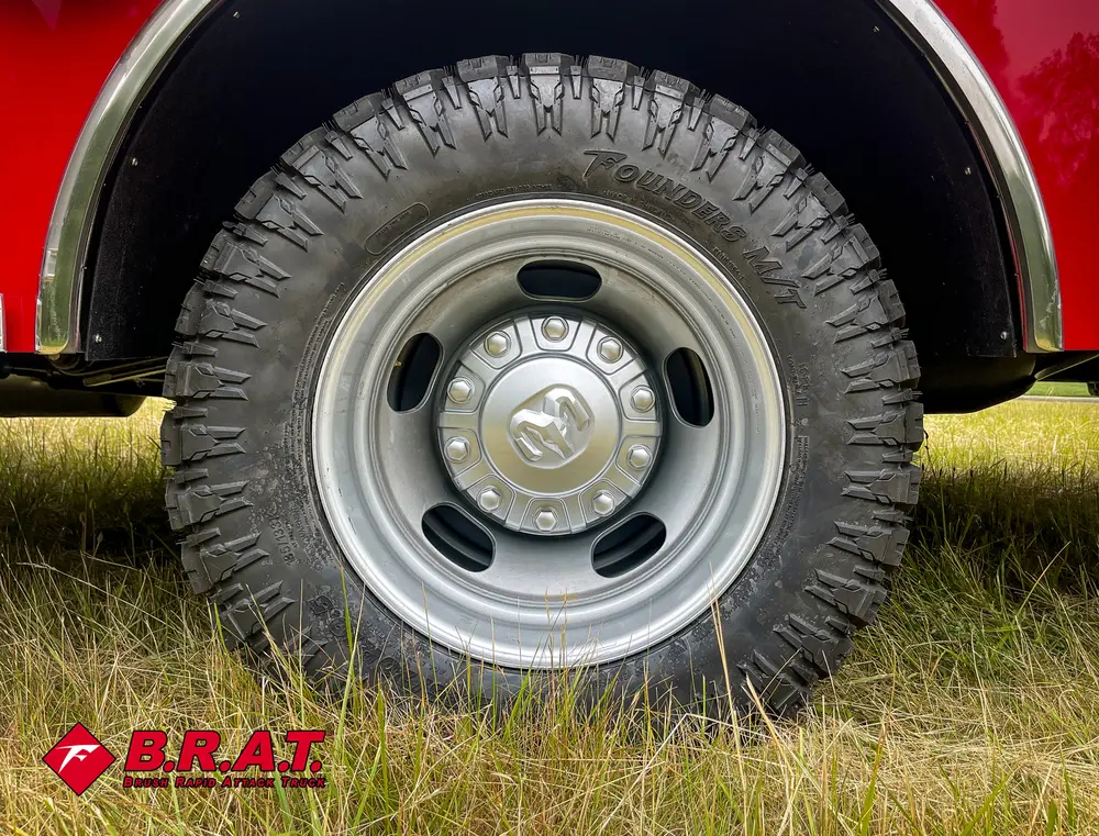 Exterior view of small fire truck showing cab, body compartments, and wheel/tire area.