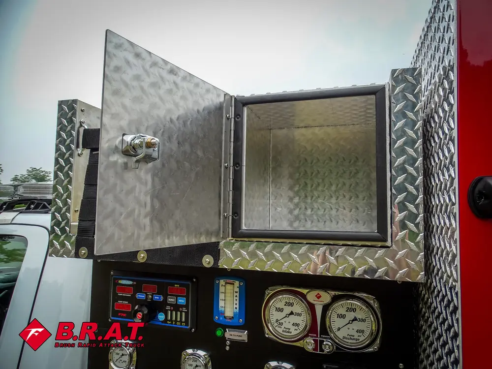 Exterior view of small fire truck showing cab, body compartments, and wheel/tire area.