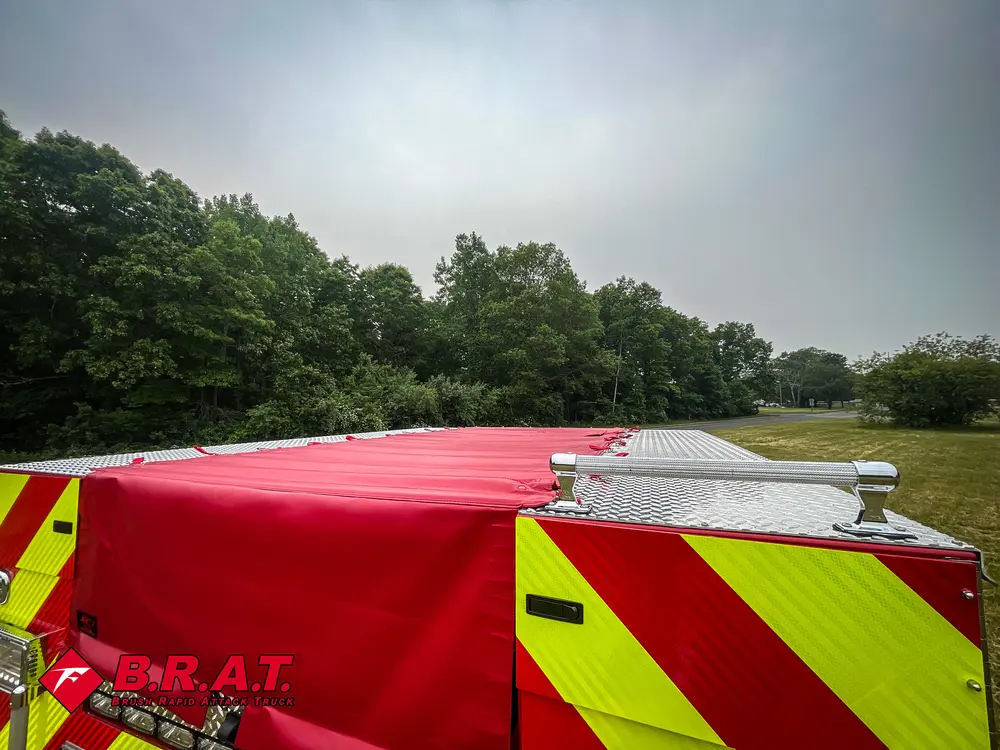 Exterior view of small fire truck showing cab, body compartments, and wheel/tire area.