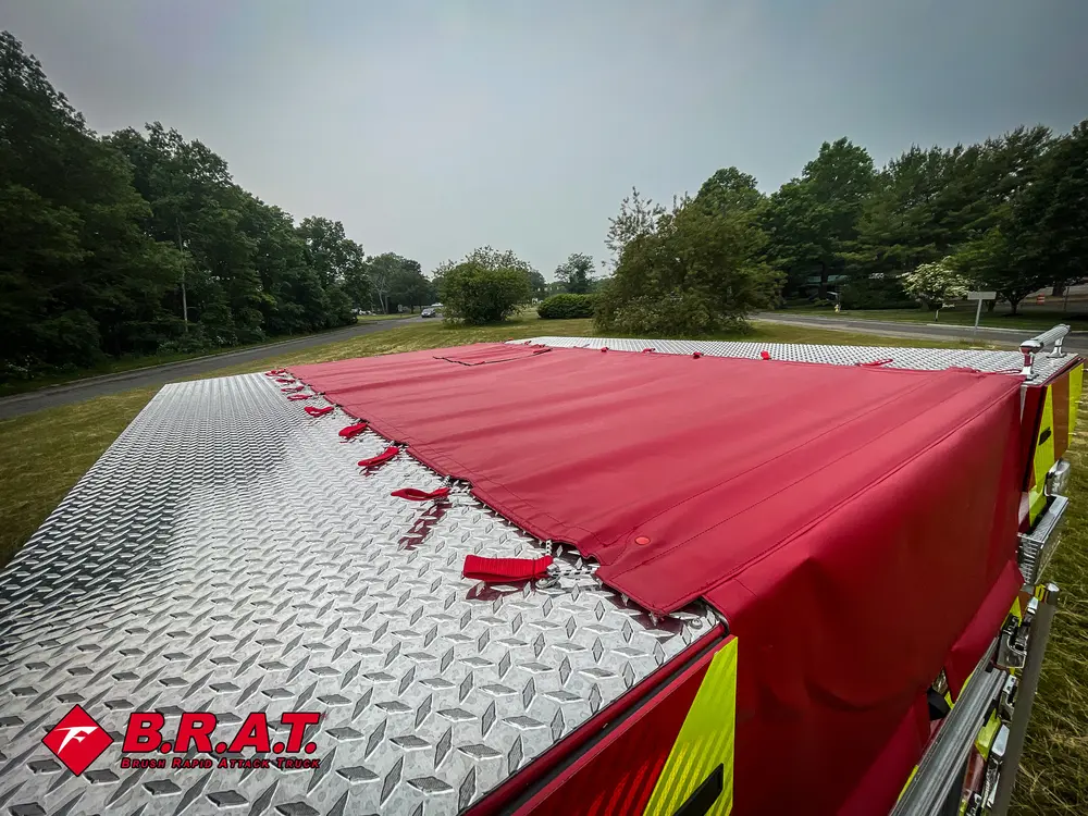 Exterior view of small fire truck showing cab, body compartments, and wheel/tire area.