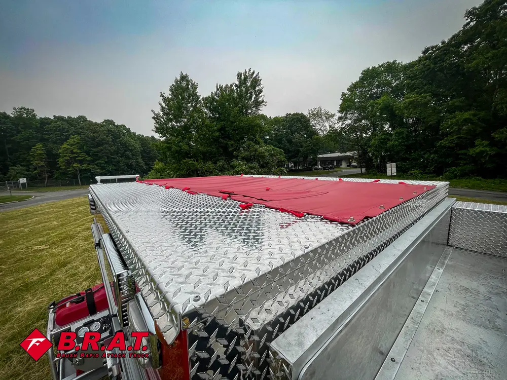 Exterior view of small fire truck showing cab, body compartments, and wheel/tire area.