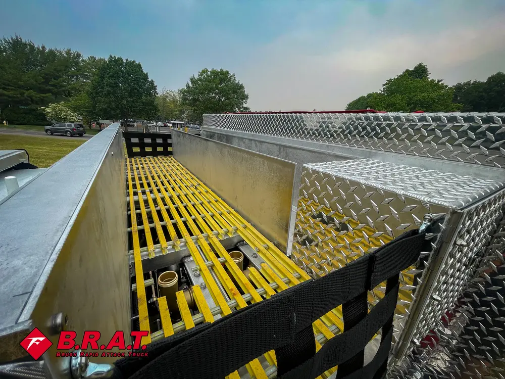 Exterior view of small fire truck showing cab, body compartments, and wheel/tire area.