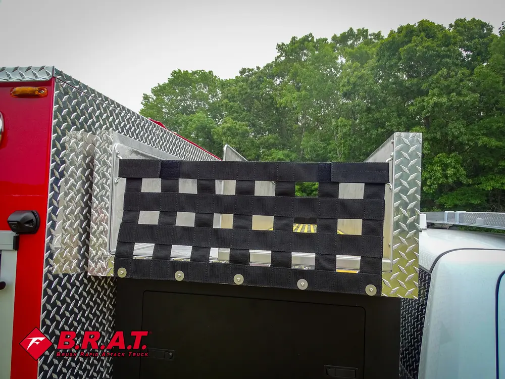 Exterior view of small fire truck showing cab, body compartments, and wheel/tire area.