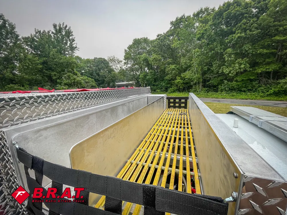 Exterior view of small fire truck showing cab, body compartments, and wheel/tire area.
