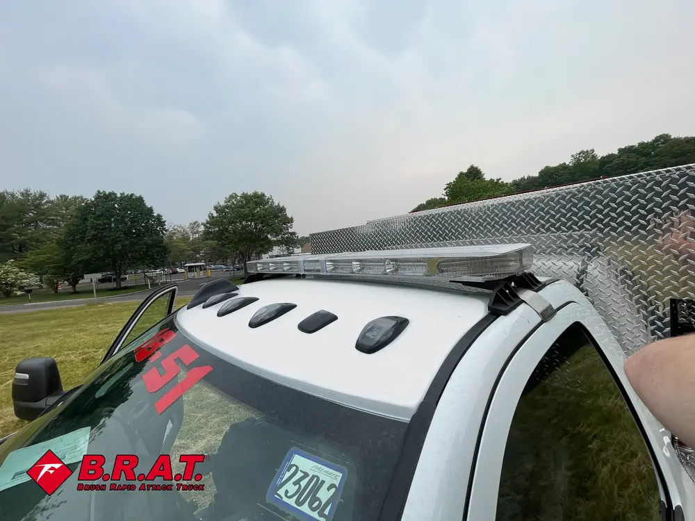 Exterior view of small fire truck showing cab, body compartments, and wheel/tire area.