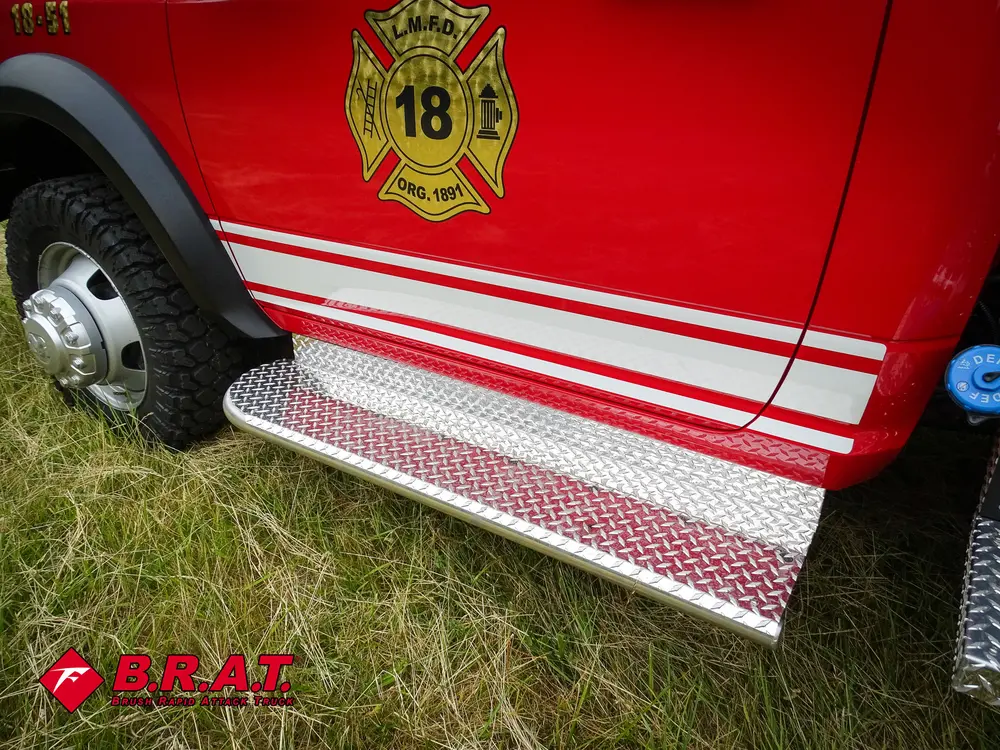 Exterior view of small fire truck showing cab, body compartments, and wheel/tire area.