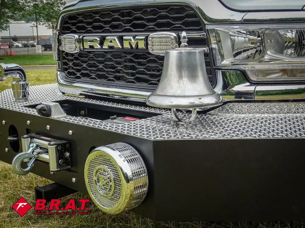 Exterior view of small fire truck showing cab, body compartments, and wheel/tire area.