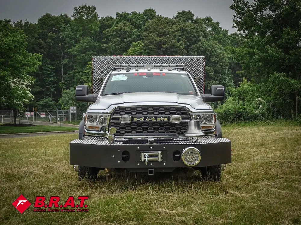 Exterior view of small fire truck showing cab, body compartments, and wheel/tire area.