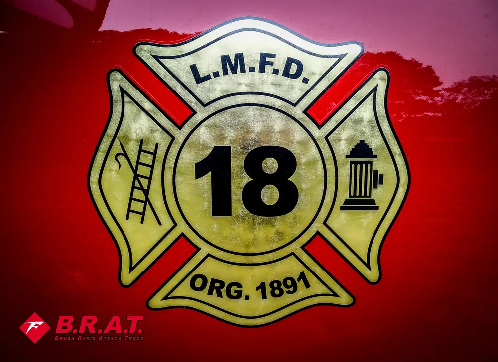 Exterior view of small fire truck showing cab, body compartments, and wheel/tire area.