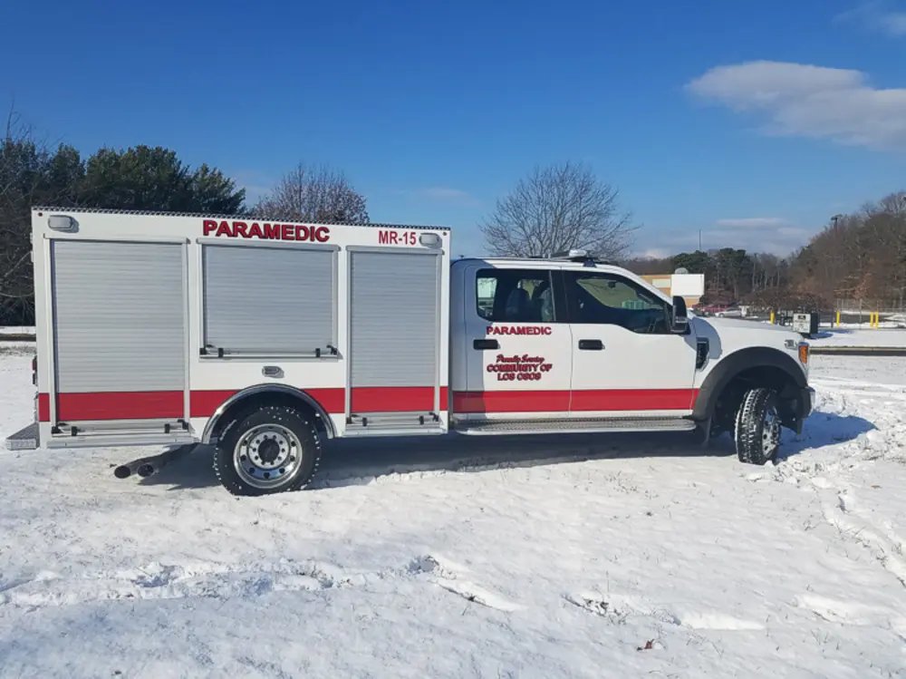 Exterior view of small fire truck showing cab, body compartments, and wheel/tire area.