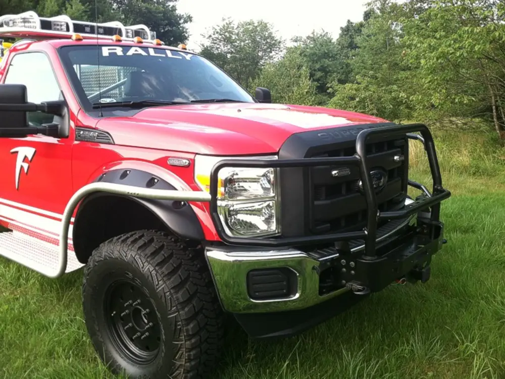 Exterior view of small fire truck showing cab, body compartments, and wheel/tire area.