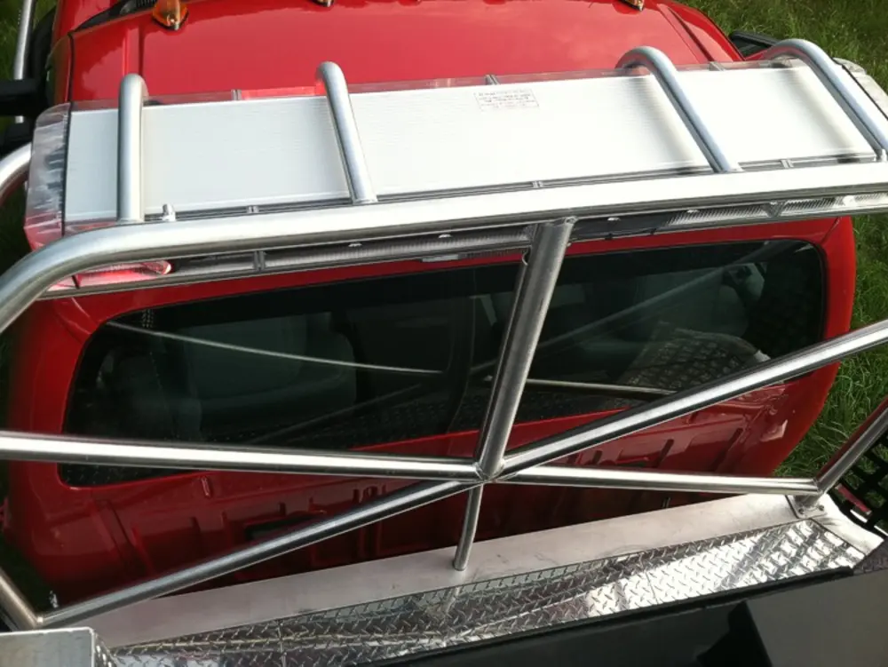 Exterior view of small fire truck showing cab, body compartments, and wheel/tire area.