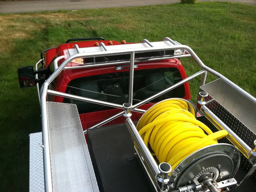 Exterior view of small fire truck showing cab, body compartments, and wheel/tire area.
