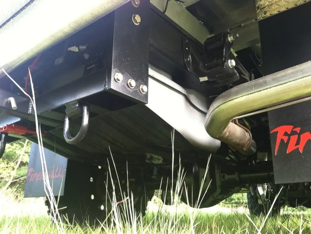 Exterior view of small fire truck showing cab, body compartments, and wheel/tire area.