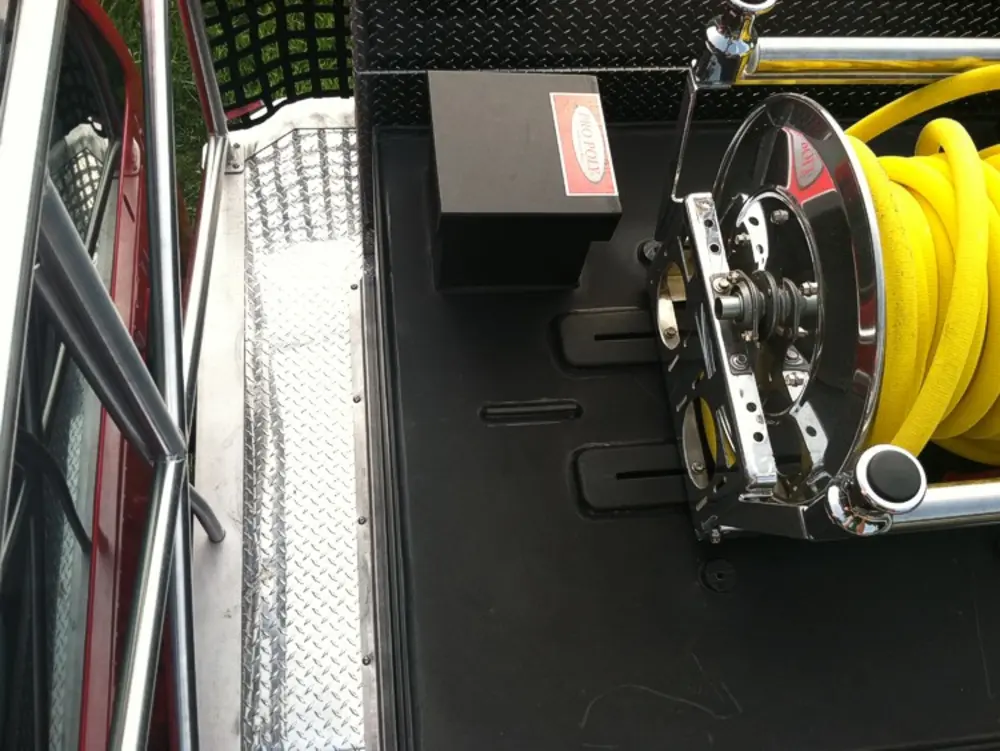 Exterior view of small fire truck showing cab, body compartments, and wheel/tire area.