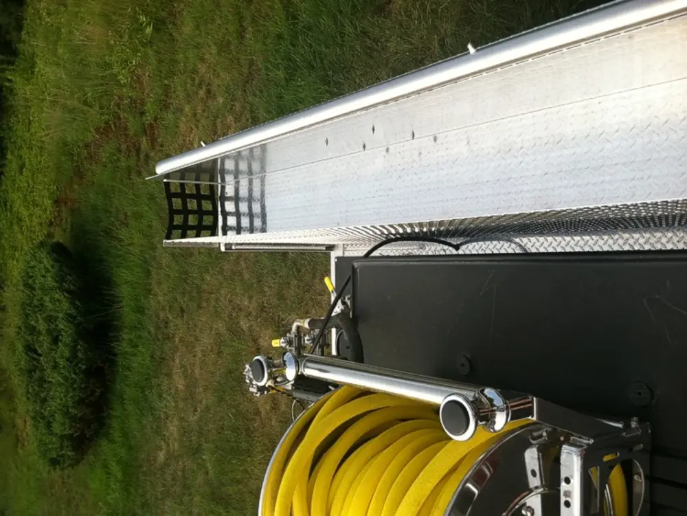 Exterior view of small fire truck showing cab, body compartments, and wheel/tire area.