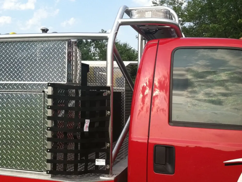 Exterior view of small fire truck showing cab, body compartments, and wheel/tire area.