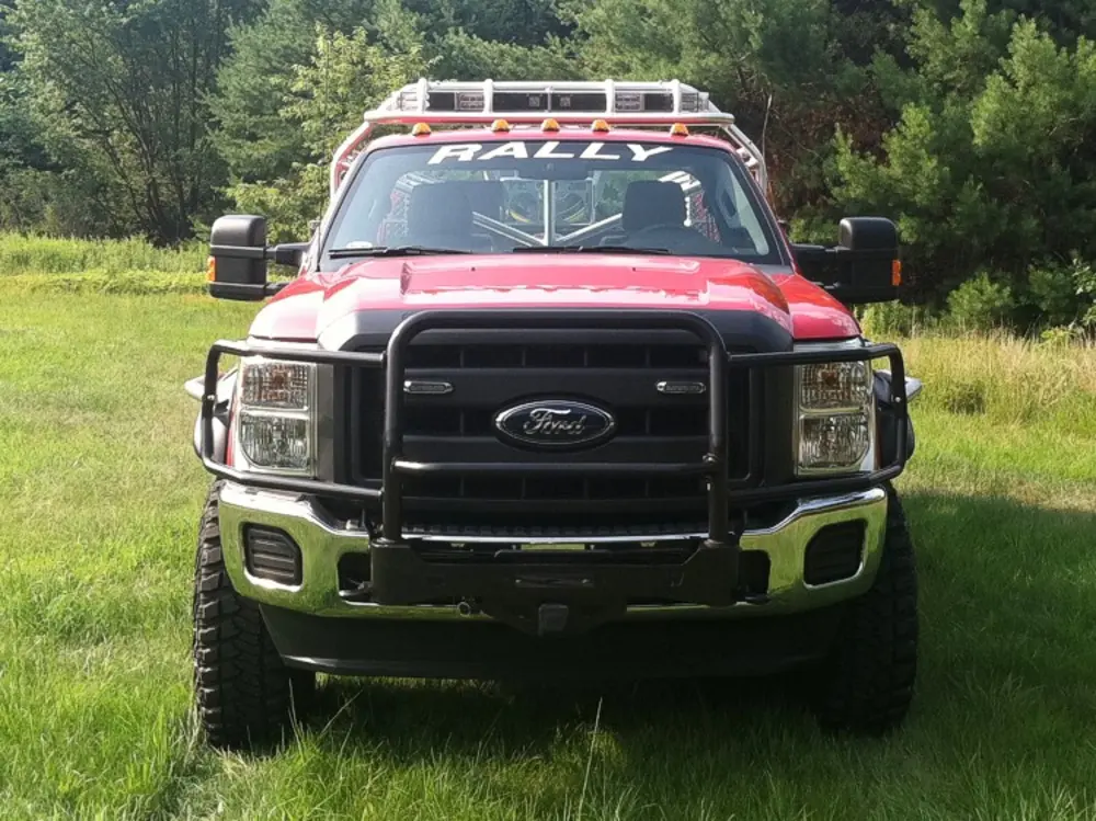 Exterior view of small fire truck showing cab, body compartments, and wheel/tire area.