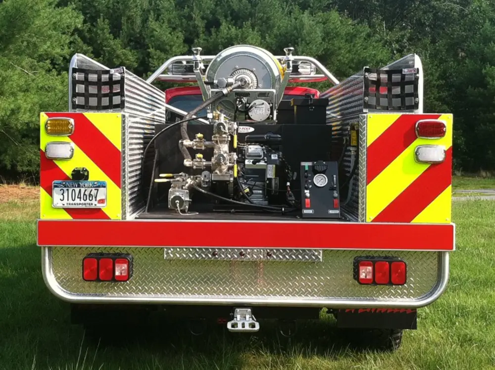 Exterior view of small fire truck showing cab, body compartments, and wheel/tire area.