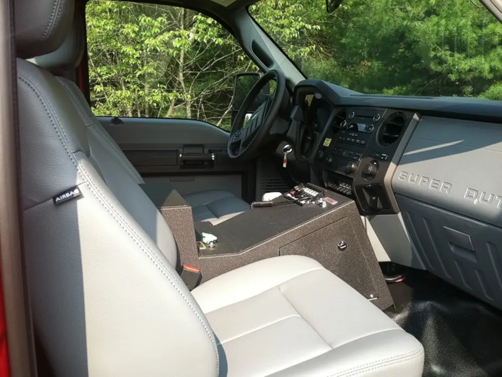 Exterior view of small fire truck showing cab, body compartments, and wheel/tire area.