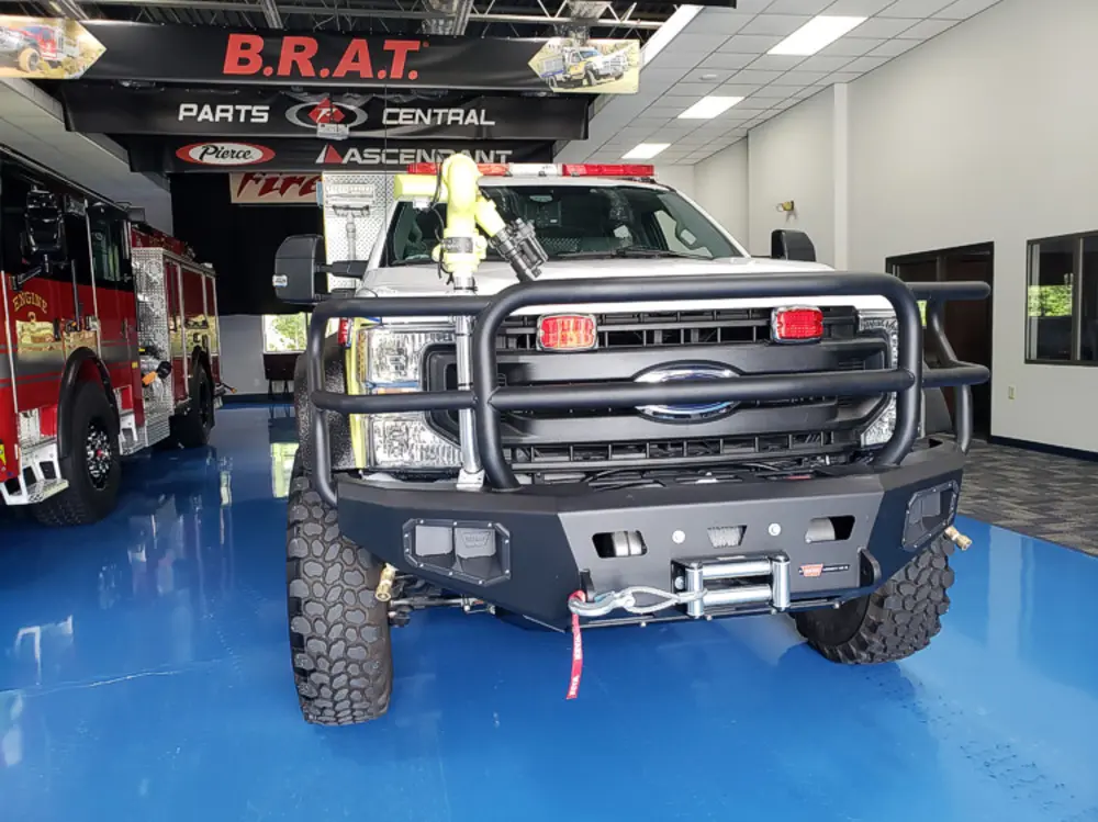Exterior view of small fire truck showing cab, body compartments, and wheel/tire area.