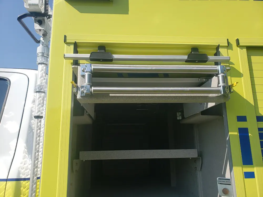 Exterior view of small fire truck showing cab, body compartments, and wheel/tire area.