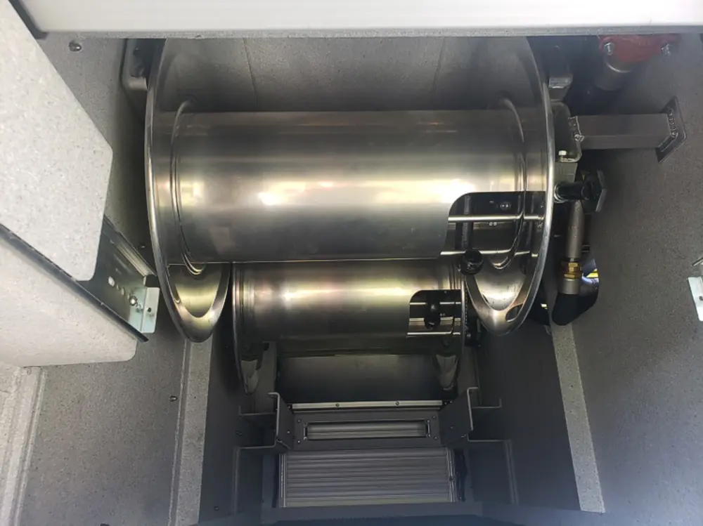 Exterior view of small fire truck showing cab, body compartments, and wheel/tire area.