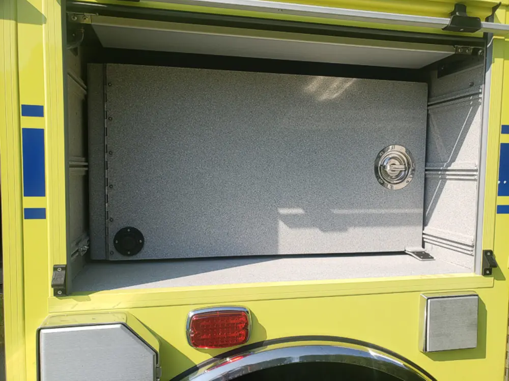 Exterior view of small fire truck showing cab, body compartments, and wheel/tire area.