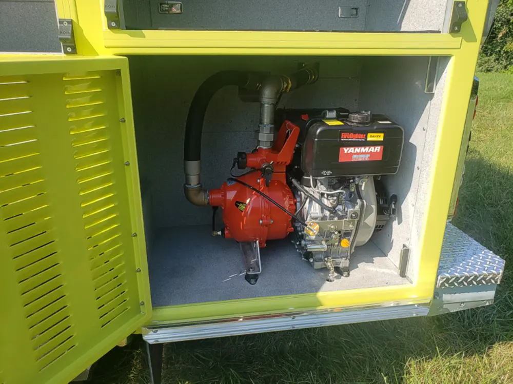 Exterior view of small fire truck showing cab, body compartments, and wheel/tire area.