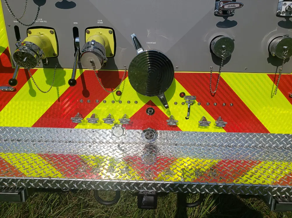 Exterior view of small fire truck showing cab, body compartments, and wheel/tire area.