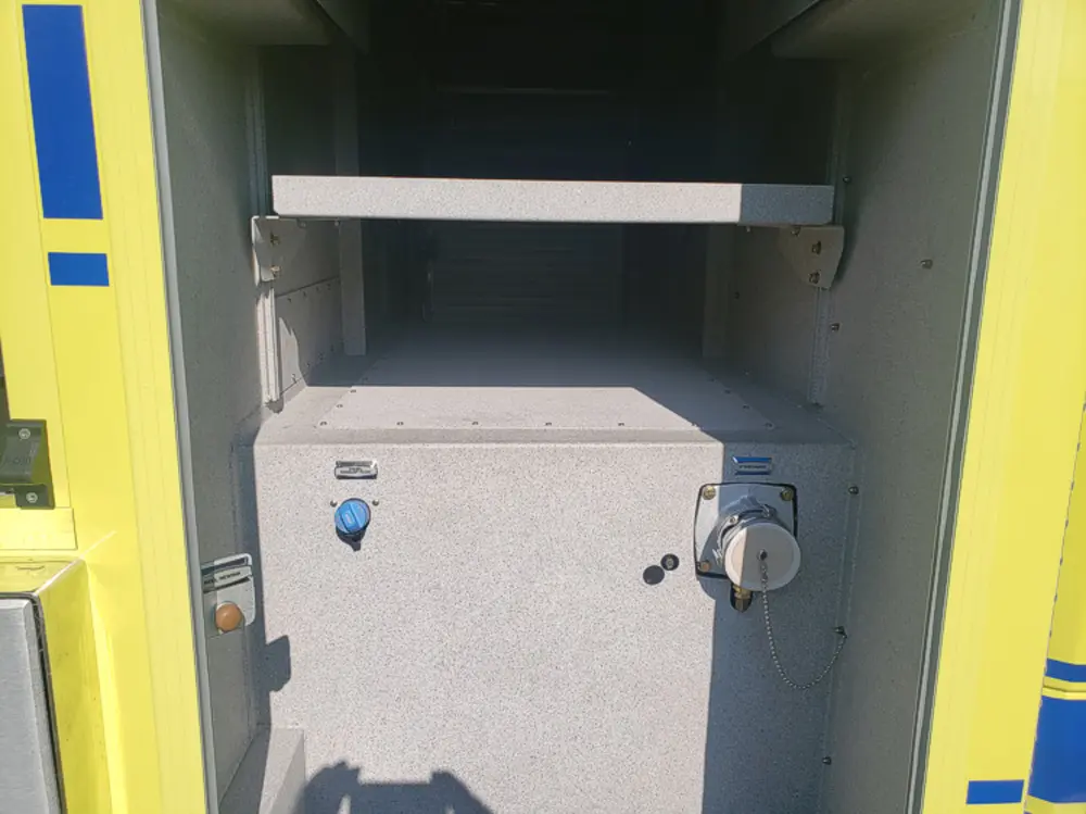 Exterior view of small fire truck showing cab, body compartments, and wheel/tire area.