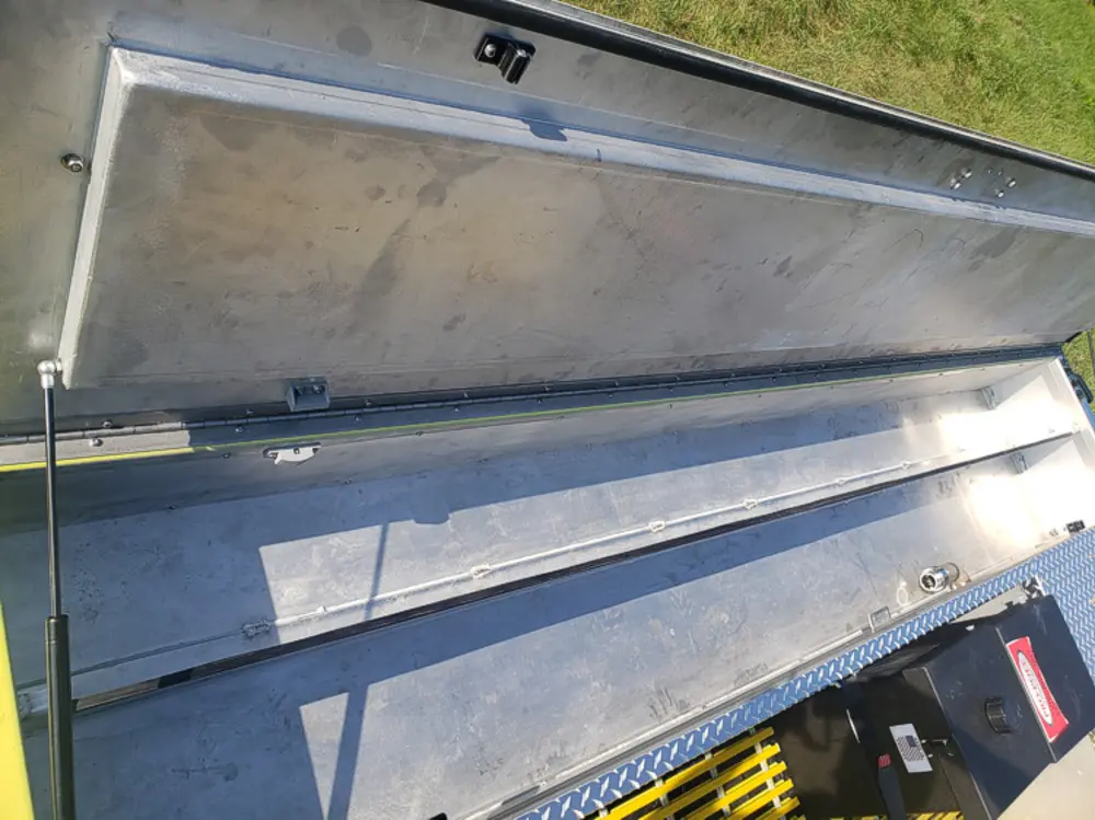 Exterior view of small fire truck showing cab, body compartments, and wheel/tire area.