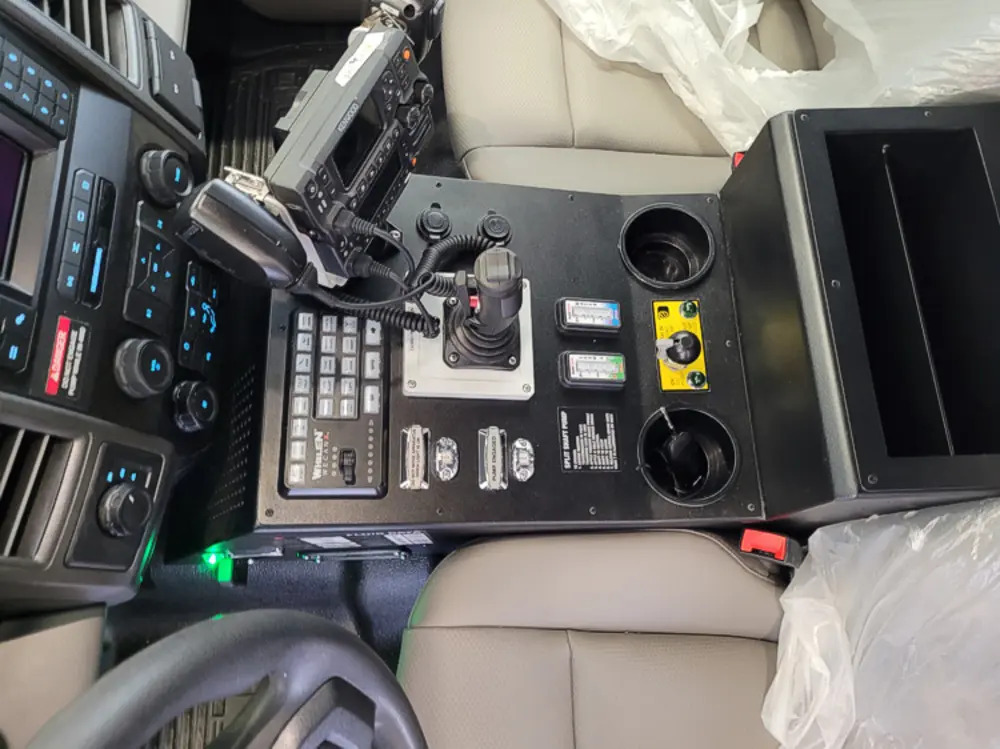 Exterior view of small fire truck showing cab, body compartments, and wheel/tire area.